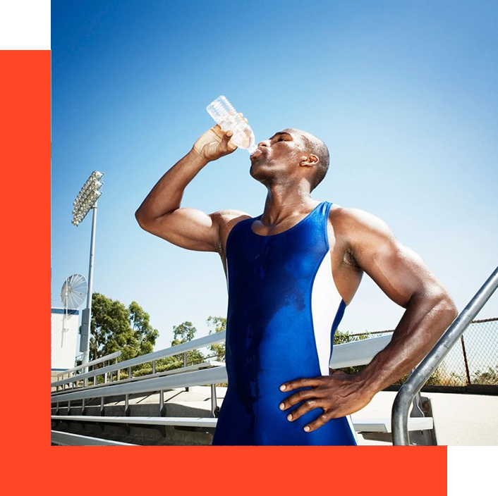 A man in blue is drinking water from a bottle