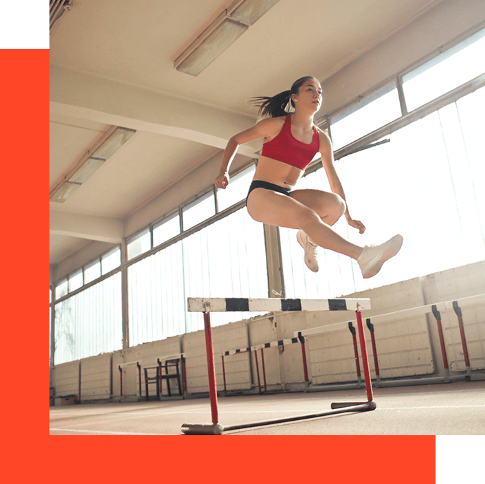 A woman jumping over an obstacle in the gym.